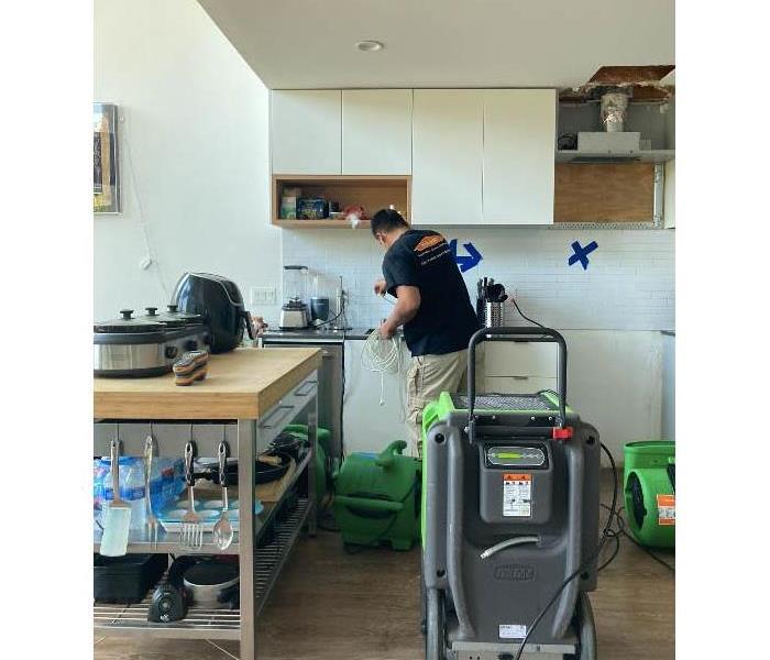 Team member setting up equipment in kitchen.